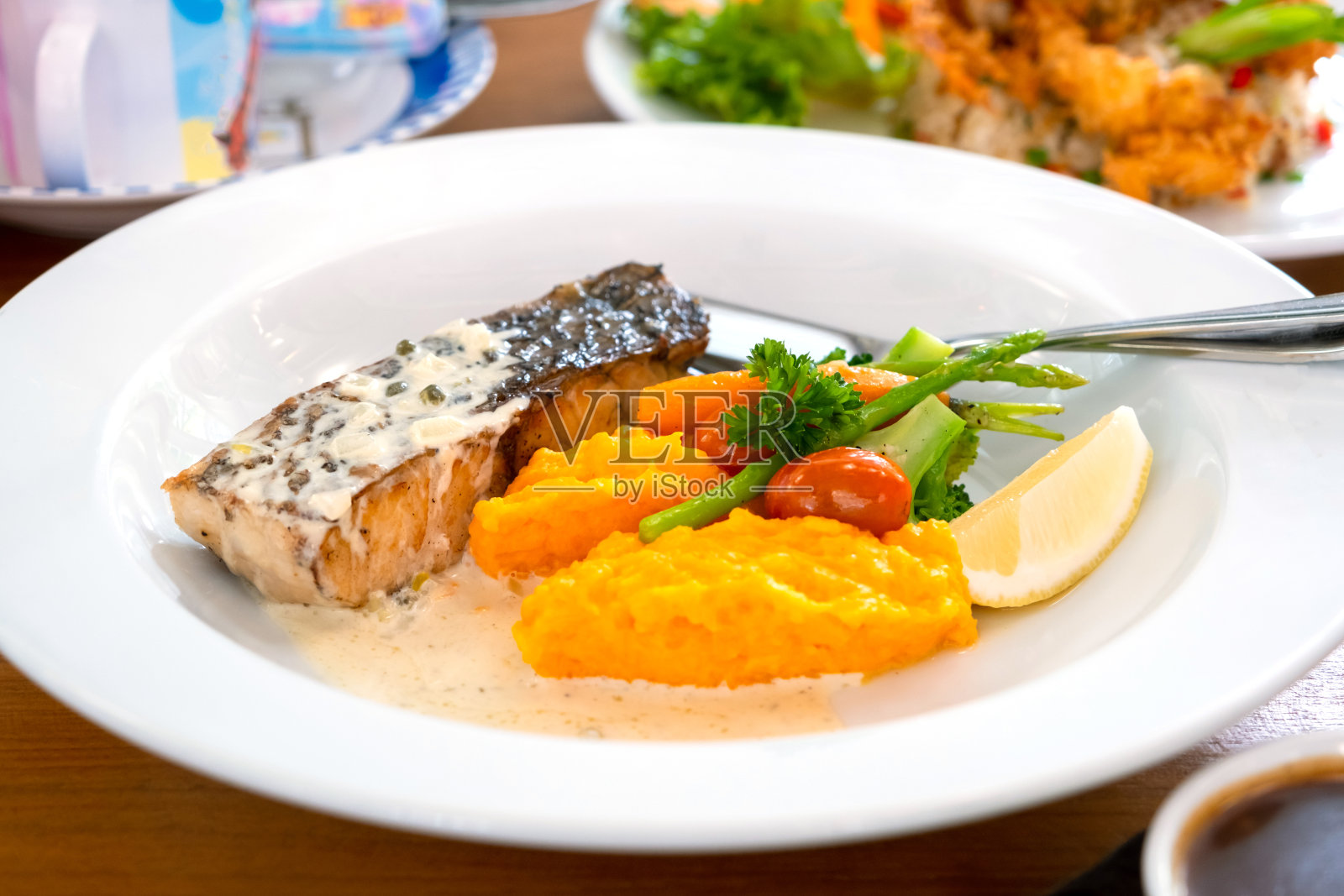 餐厅餐桌上的白色盘子里的鲑鱼排照片摄影图片