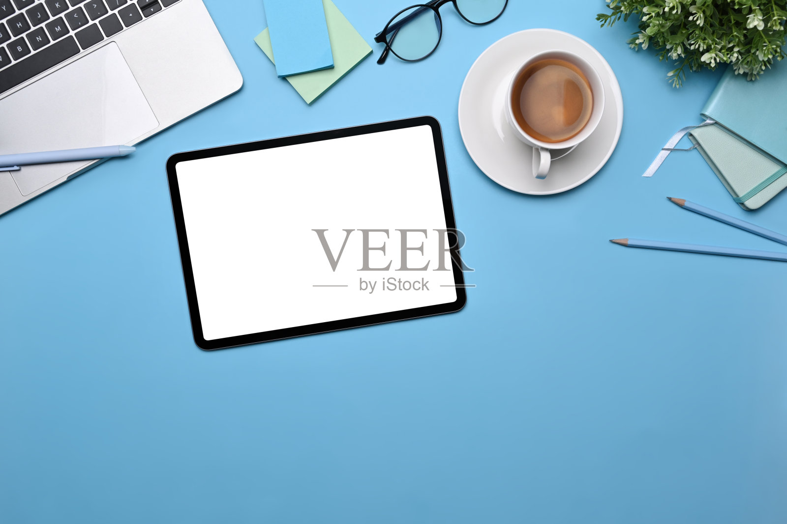 顶视图数码平板电脑,咖啡杯,便利贴和笔记本电脑的蓝色背景。照片摄影图片