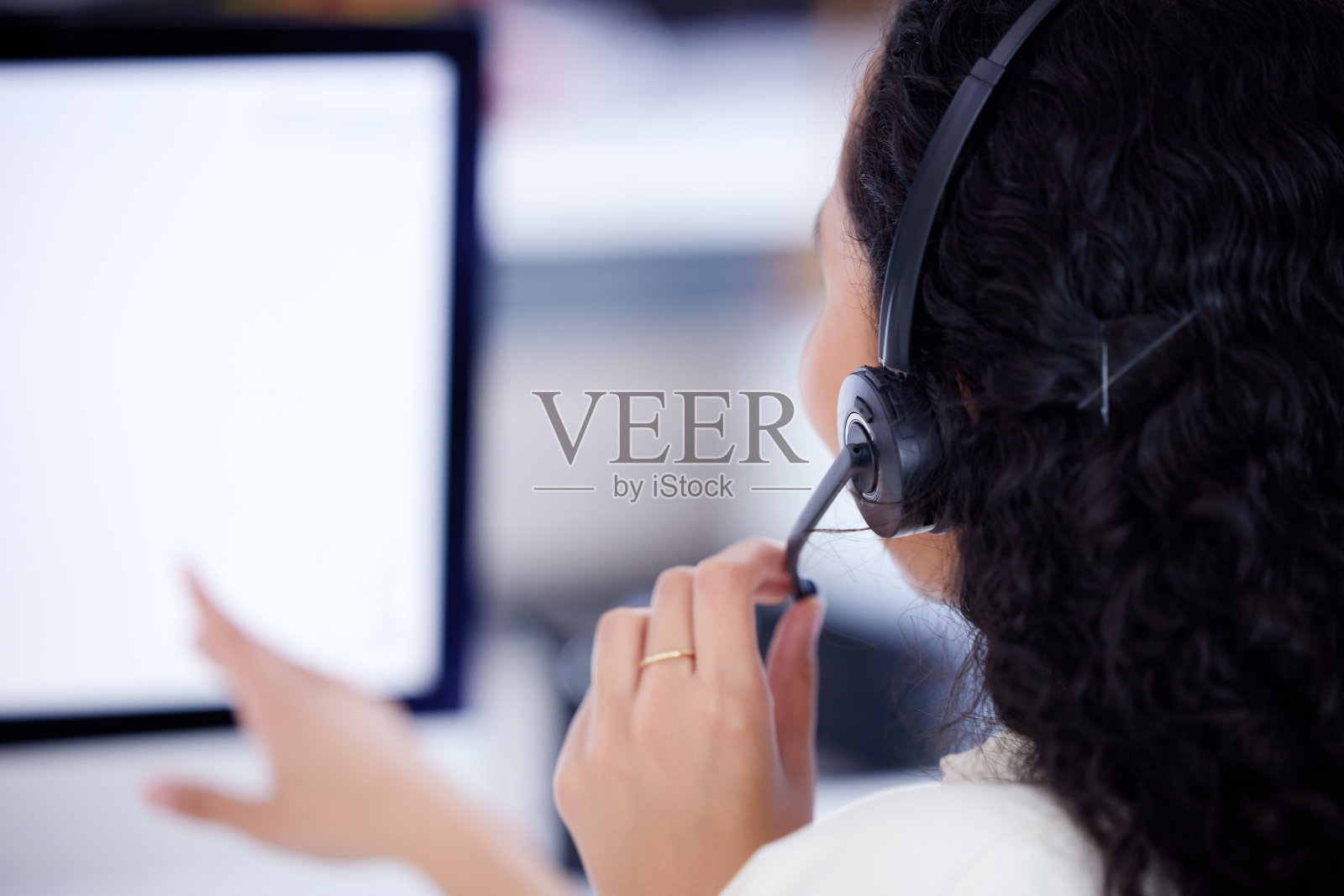 一个呼叫中心座席在办公室的电脑上工作的后视镜照片摄影图片