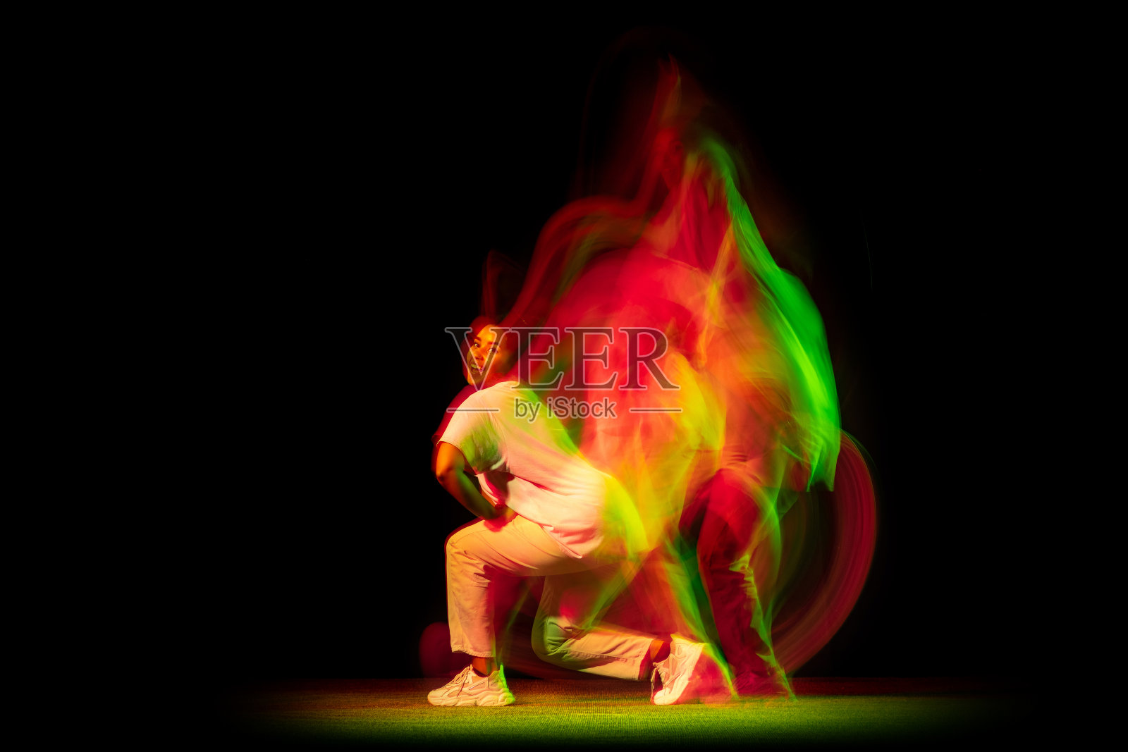 工作室拍摄的年轻活跃的女孩跳舞街舞孤立在黑暗的背景霓虹灯混合黄绿光。照片摄影图片