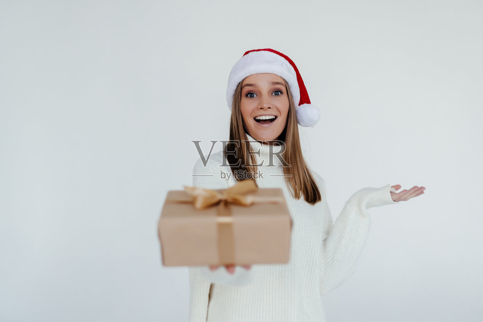 快乐兴奋的年轻女子在圣诞老人的帽子与礼盒在白色的背景照片摄影图片