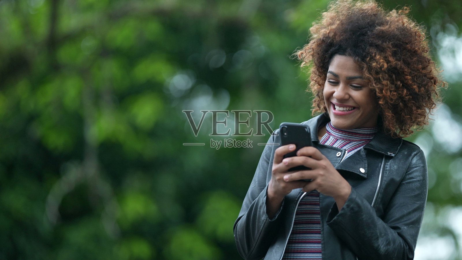 激动的黑人妇女在电话通知上庆祝好消息。人们收到积极的信息照片摄影图片