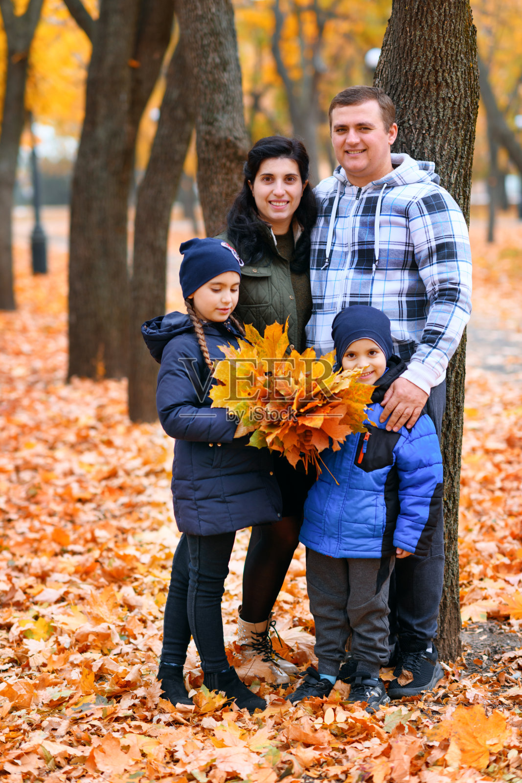 一个家庭和孩子们在秋天的城市公园的肖像-快乐的人们在一起摆姿势,美丽的自然与黄色的叶子作为背景。照片摄影图片