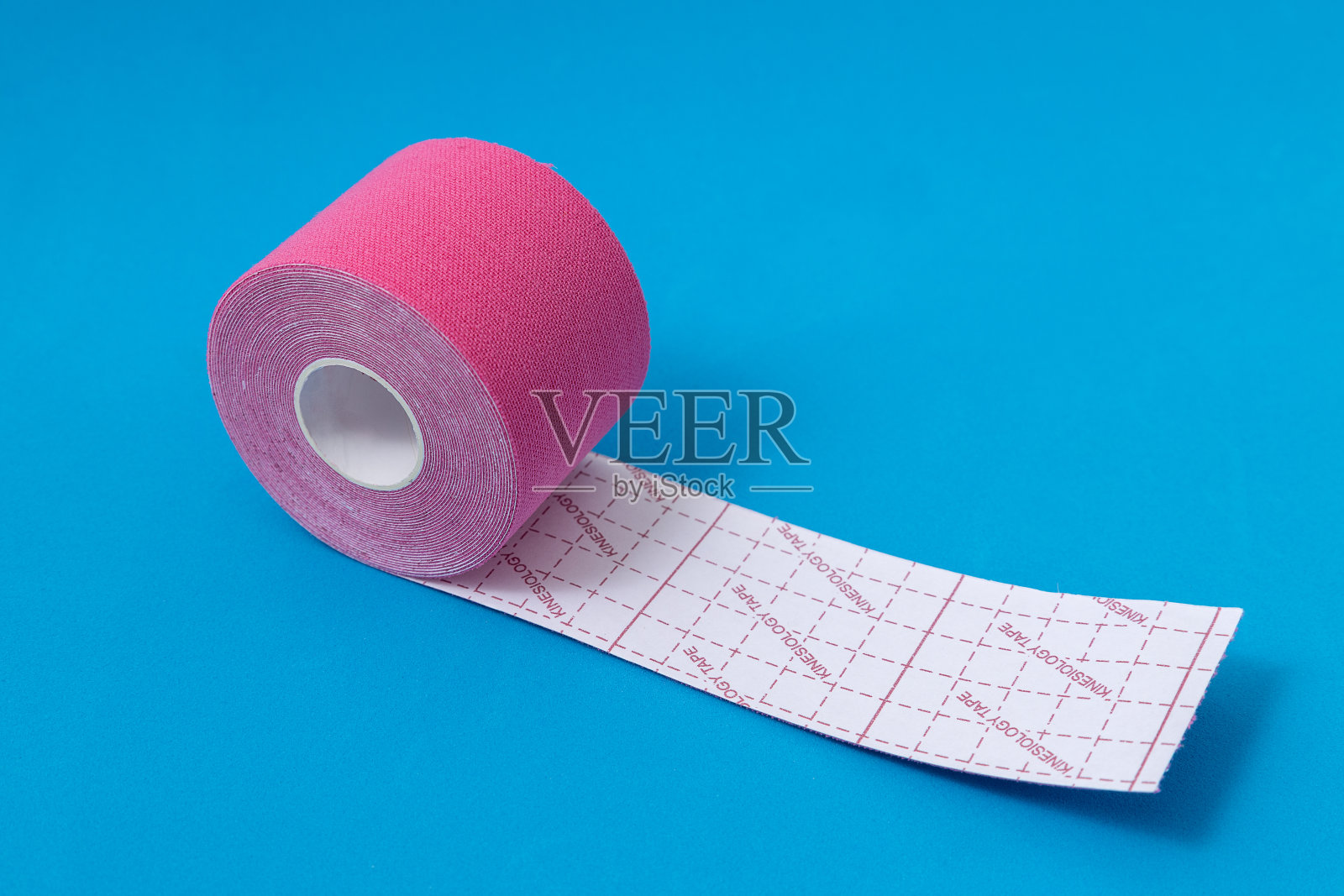 在明亮的蓝色表面上的粉色医用肌内效带的特写照片摄影图片