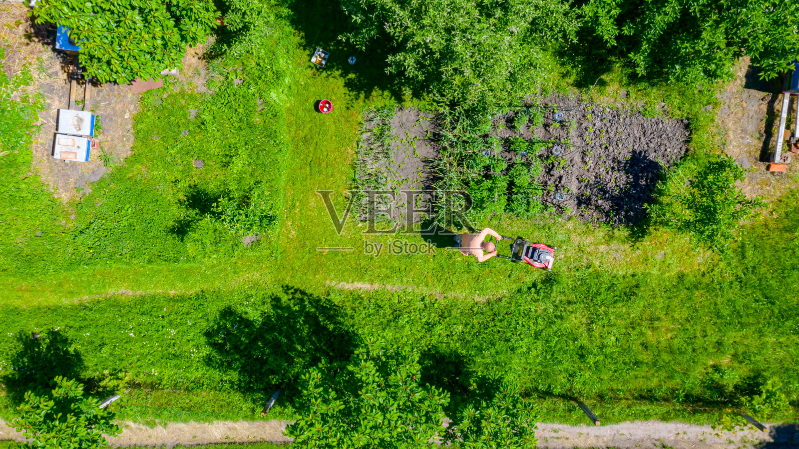 农民用汽油割草机在花园里修剪草坪的鸟瞰图照片摄影图片