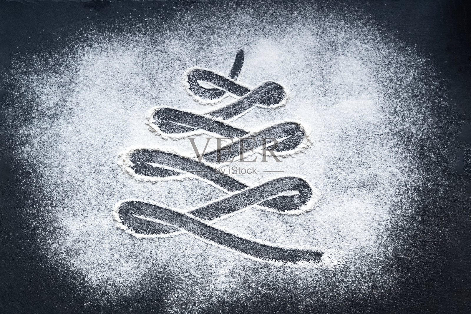 撒了面粉的桌子上手绘的圣诞树。照片摄影图片