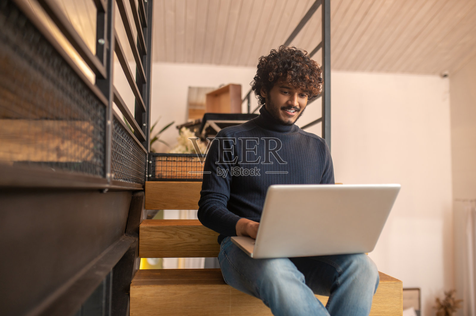 坐在楼梯上看着笔记本电脑屏幕的男人照片摄影图片