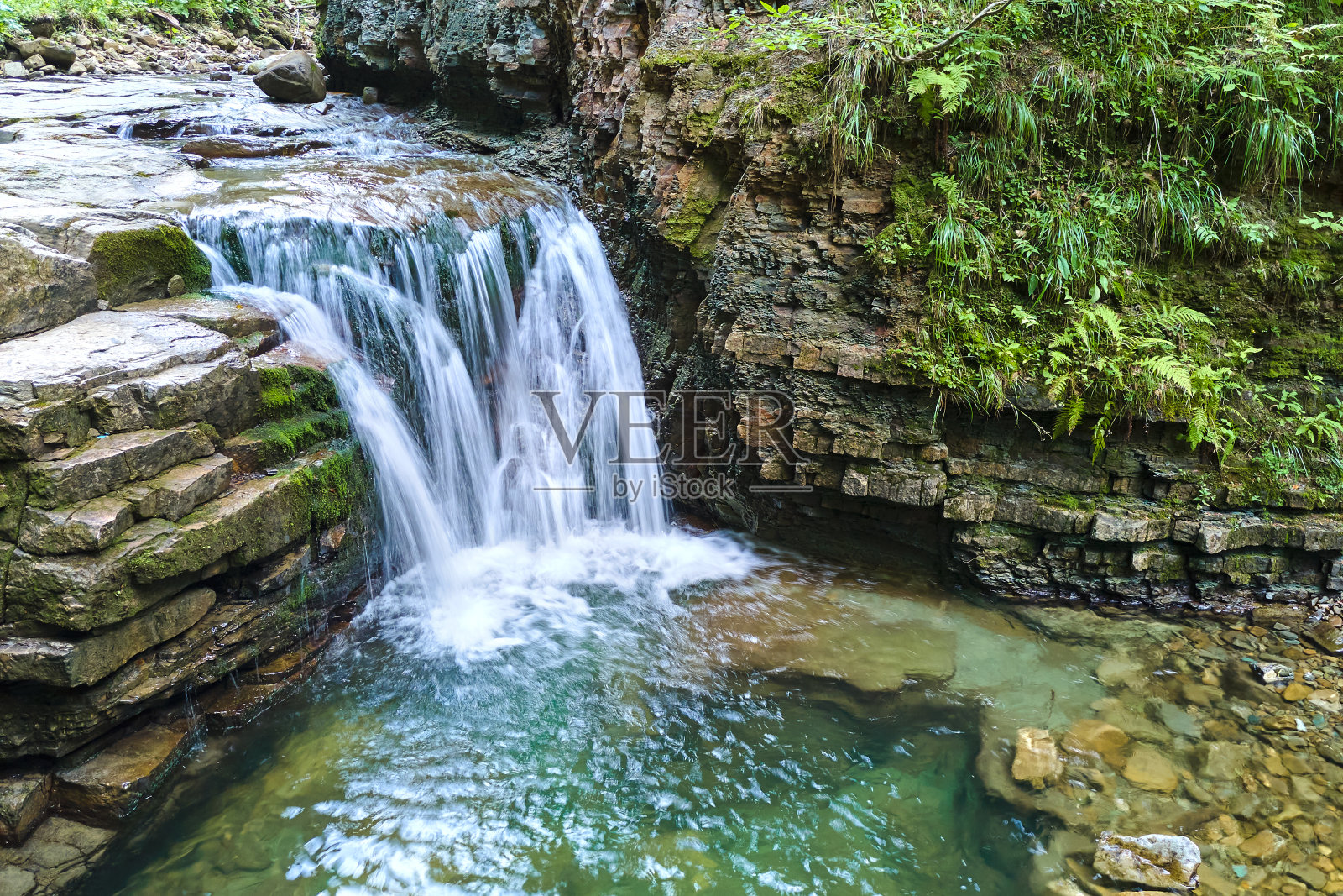 在夏天的热带雨林中,美丽的山河瀑布和白色的泡沫水从岩石悬崖上落下。照片摄影图片