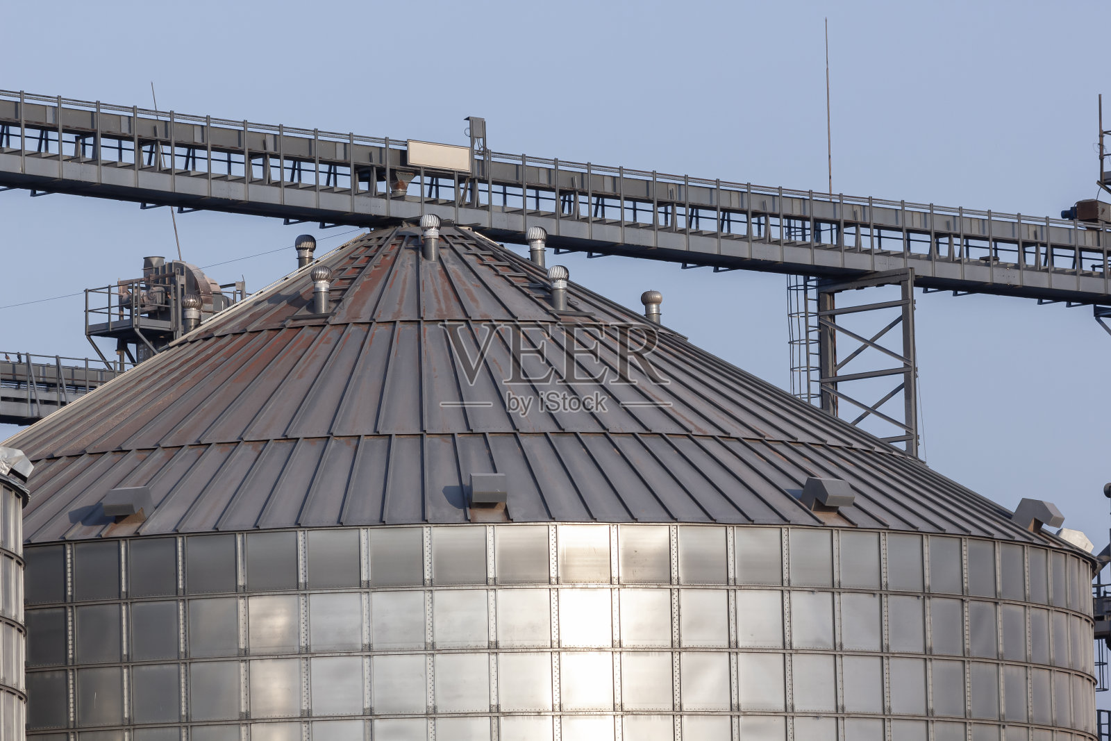 粮食加工厂用于储存和加工粮食作物的大型现代加工厂在阳光明媚的日子里看到的粮仓。大铁桶谷物。银筒仓在农业制造工厂用于加工和干燥照片摄影图片