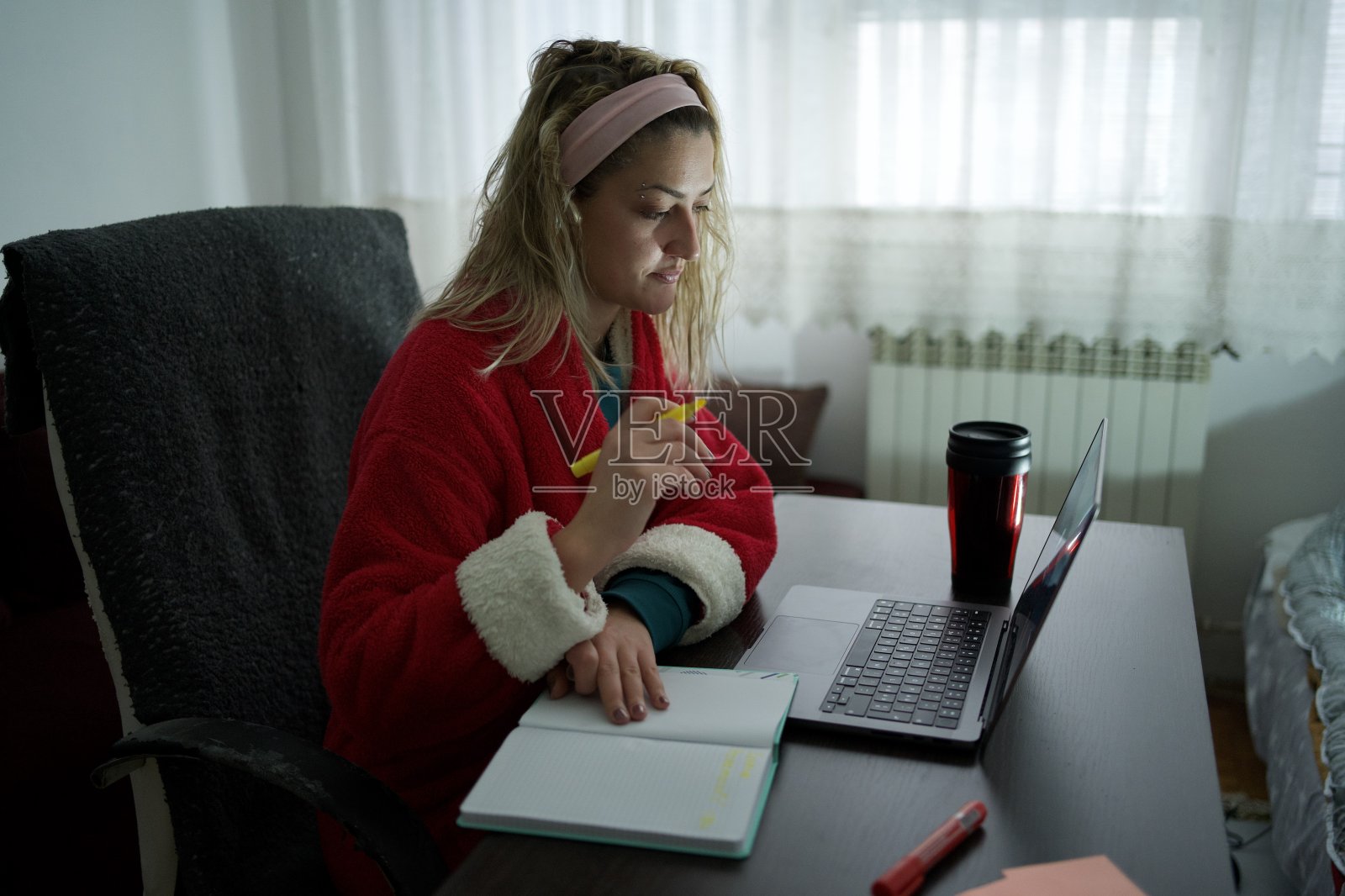 女孩分析了笔记本电脑上的文件,准备写下她的观察结果照片摄影图片