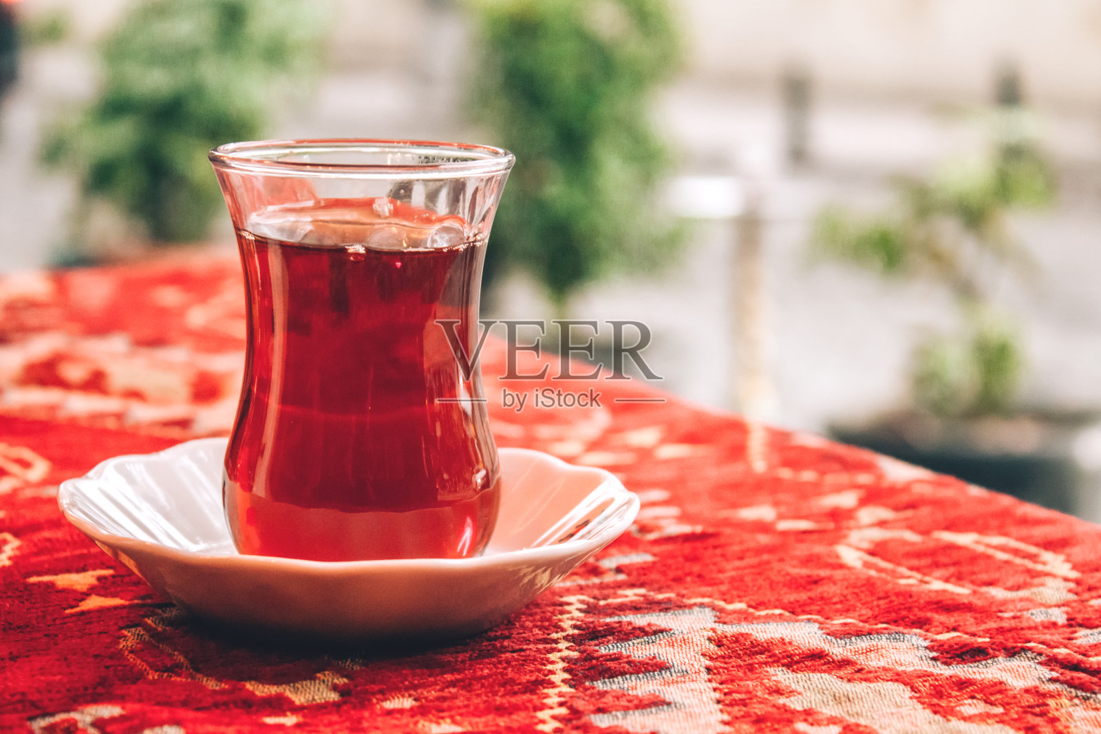 传统的土耳其茶在特殊的郁金香形状的玻璃上红色的桌布。有选择性的重点。带有复制空间的散焦背景照片摄影图片