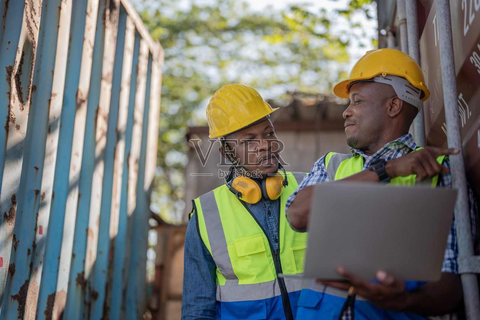 非洲工人、工程师、技术员手持手提电脑,检查现场集装箱区域,准备运输。概念人操作在重工业。照片摄影图片