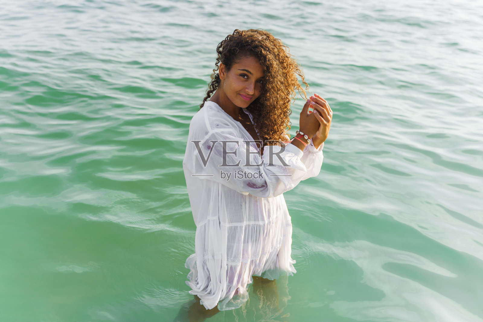 卷发女人站在海中微笑。幸福的概念照片摄影图片