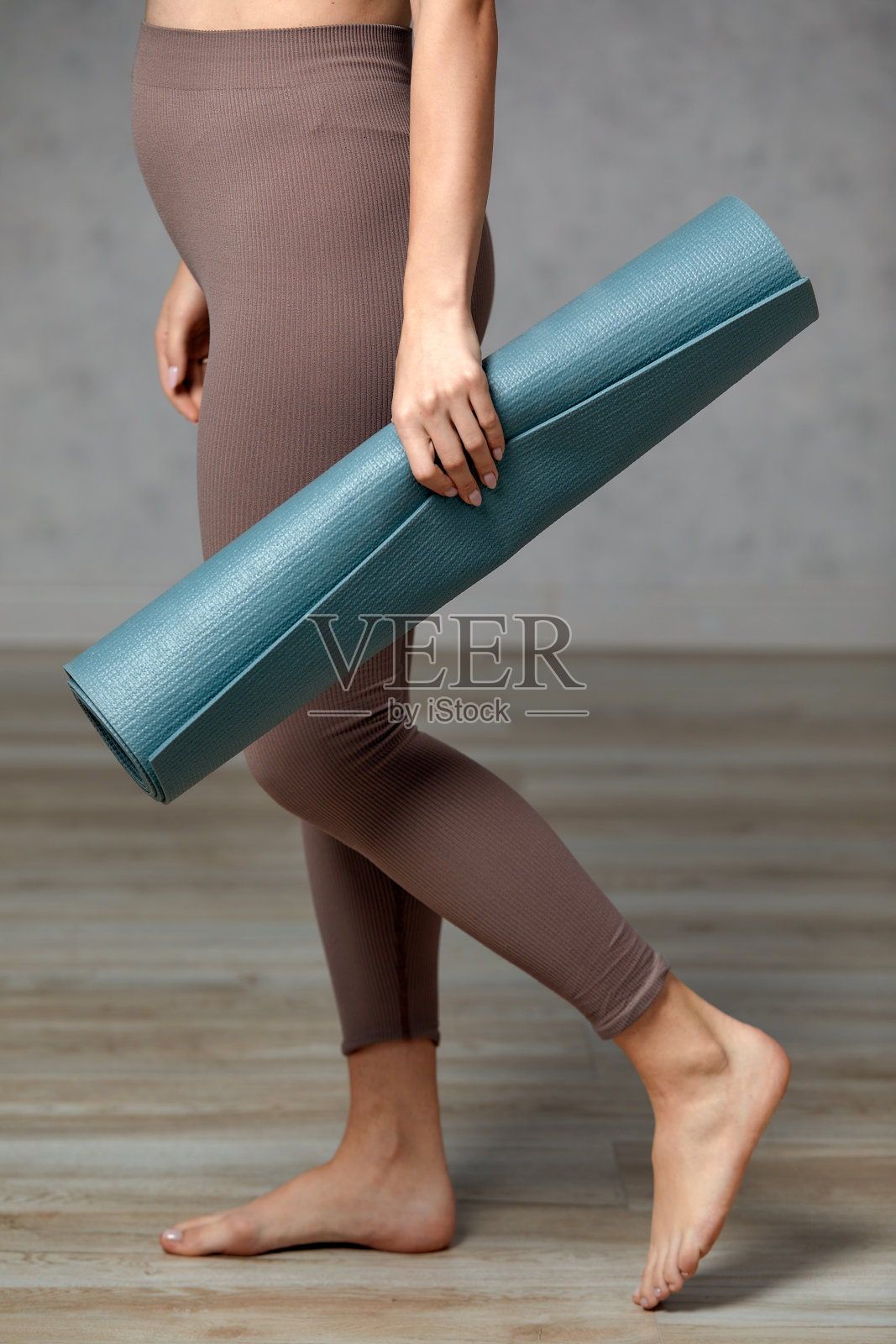 孕妇面带微笑,穿着运动服,准备晨操或锻炼。快乐的年轻女性在怀孕期间遵循健康的生活方式,抱着瑜伽垫做普拉提或伸展运动照片摄影图片