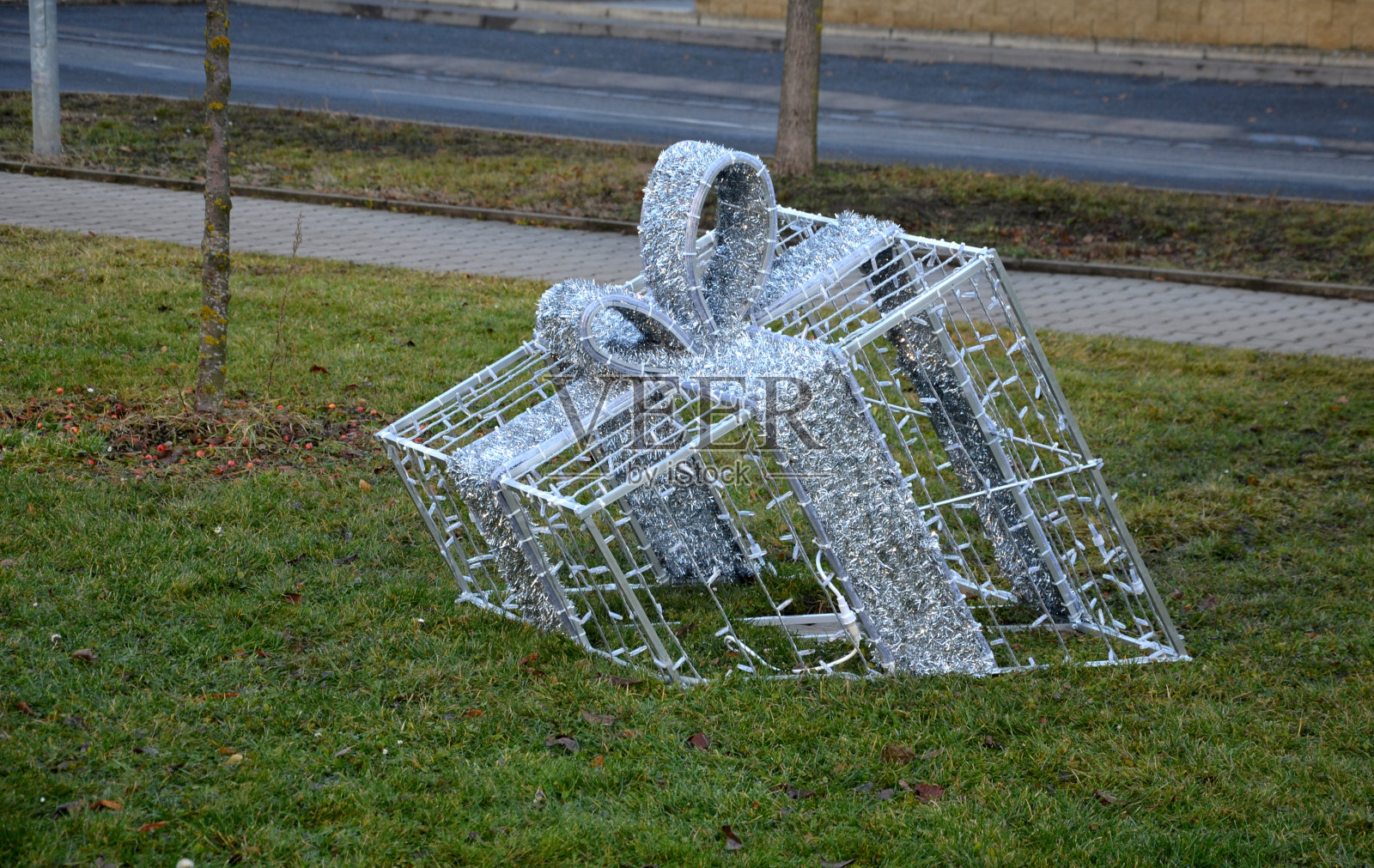 圣诞节装饰在方形的彩带礼盒上。电线盒包裹在发光的LED链。装饰好像来自草坪。豪华假日广场照片摄影图片