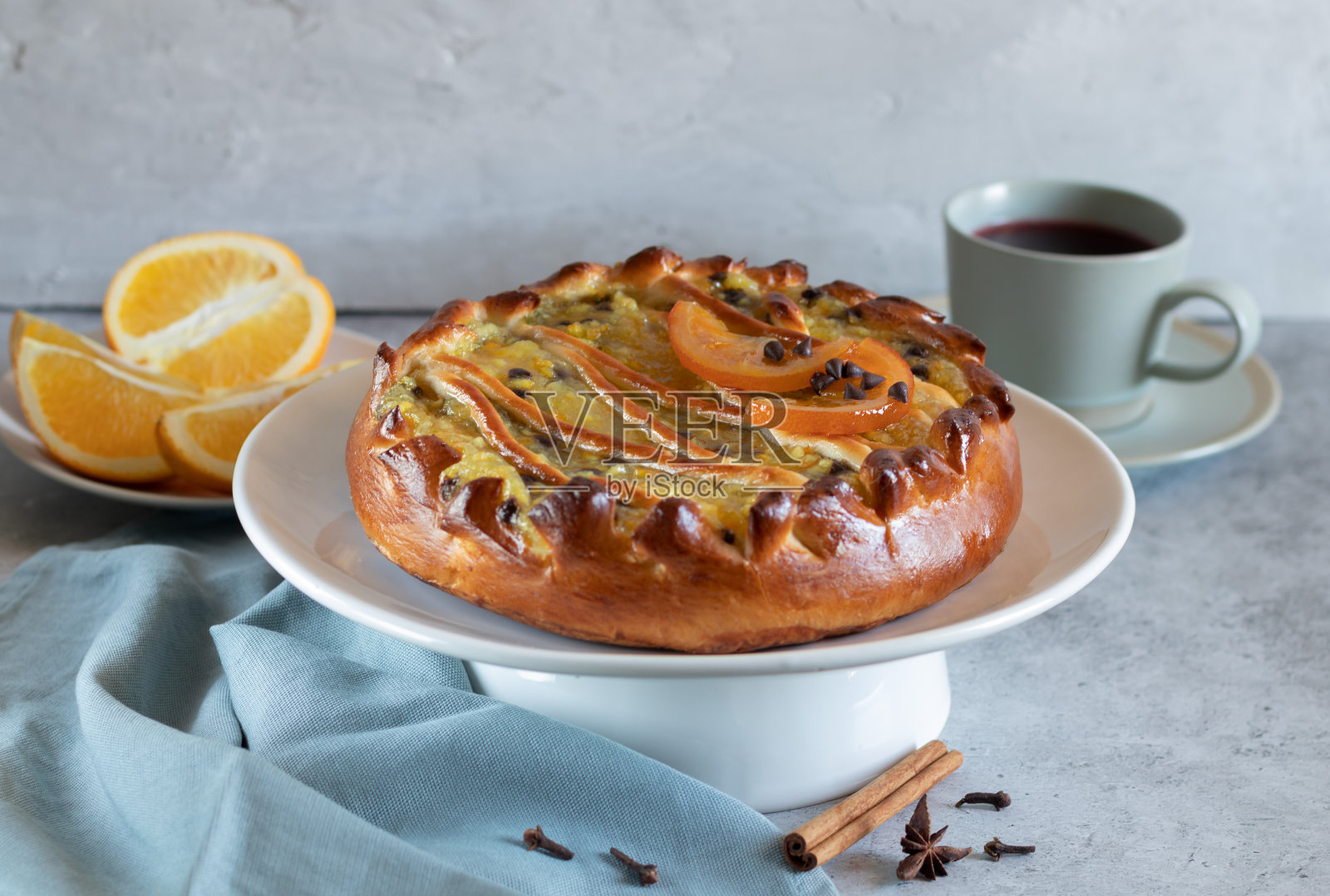 橙子馅的馅饼。一杯茶,淡色的背景和灰色的纺织品照片摄影图片