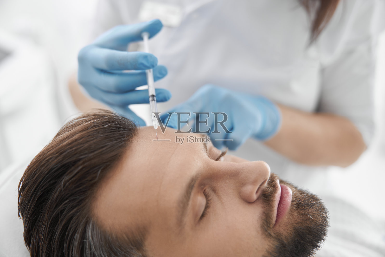 美容师在美容院的成熟病人上手套做填充物注射照片摄影图片