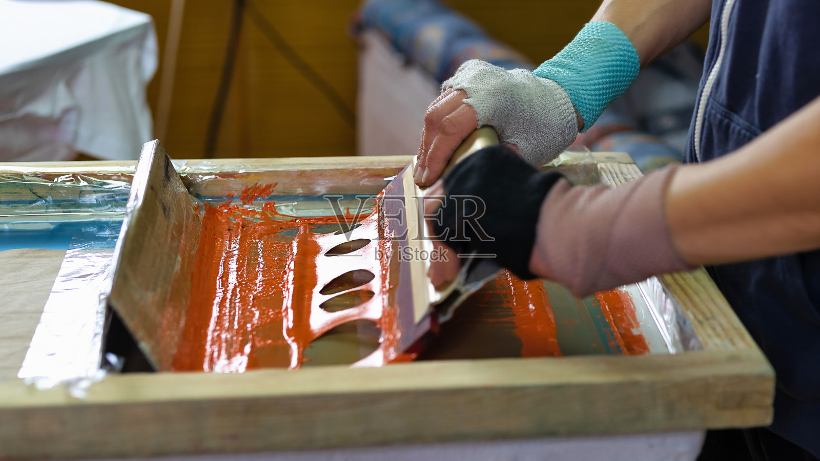 在车间制作t恤印花。绢印生产。在设计工作室把图案印在衣服上照片摄影图片