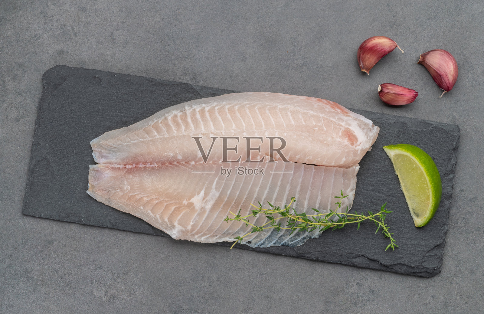 生罗非鱼片与调味料石头背景照片摄影图片