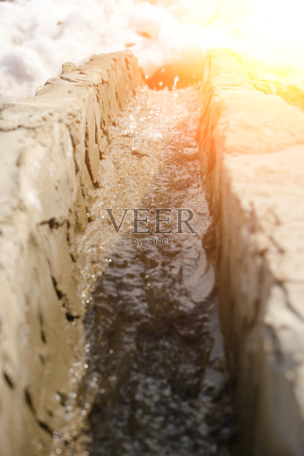 解冻的泉水顺着滑槽流下。明媚,阳光明媚,春天的一天。照片摄影图片