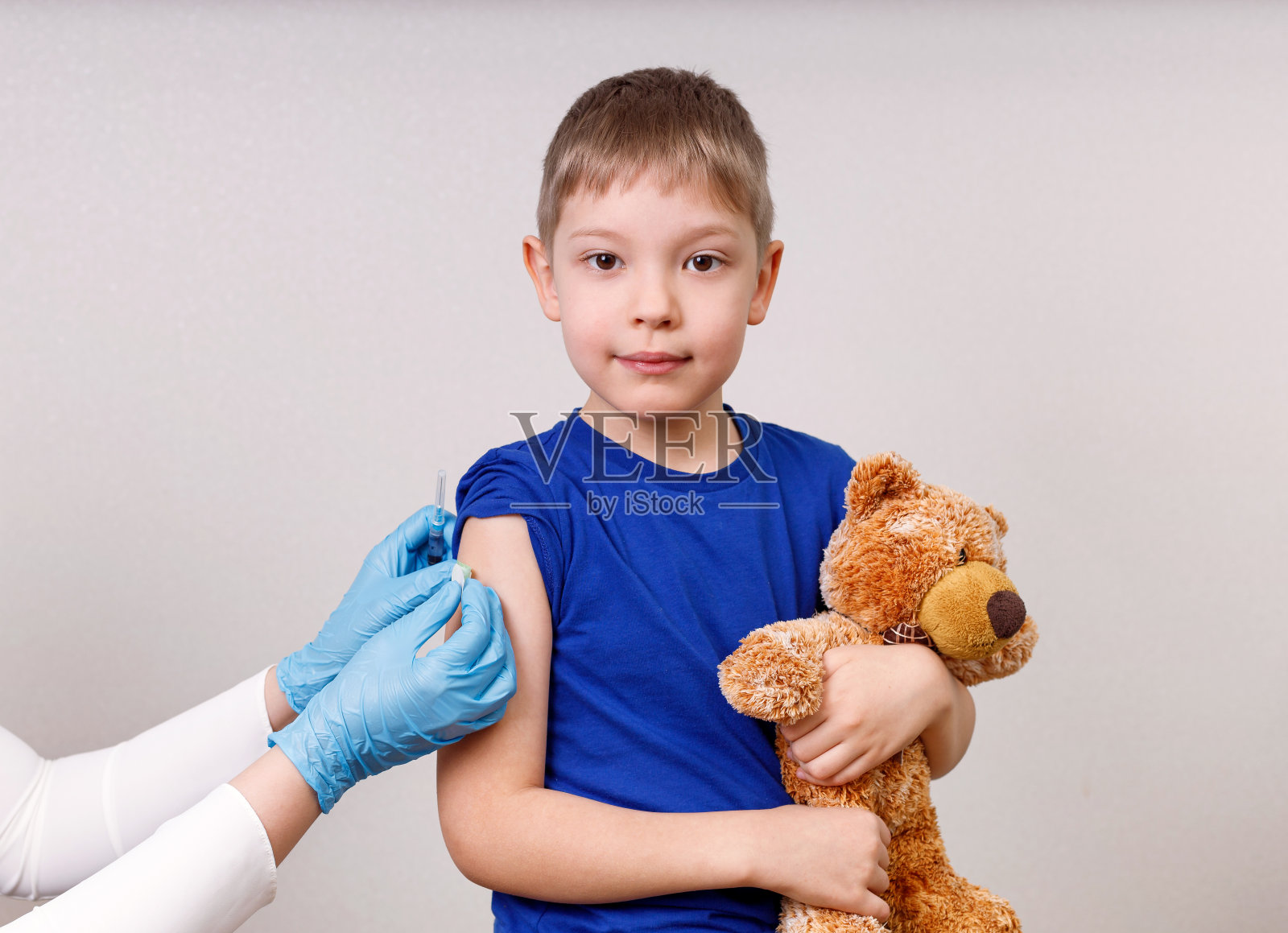 儿科医生给一个穿蓝色t恤的小男孩接种了疫苗,并给他打了石膏。接种疫苗的概念。照片摄影图片