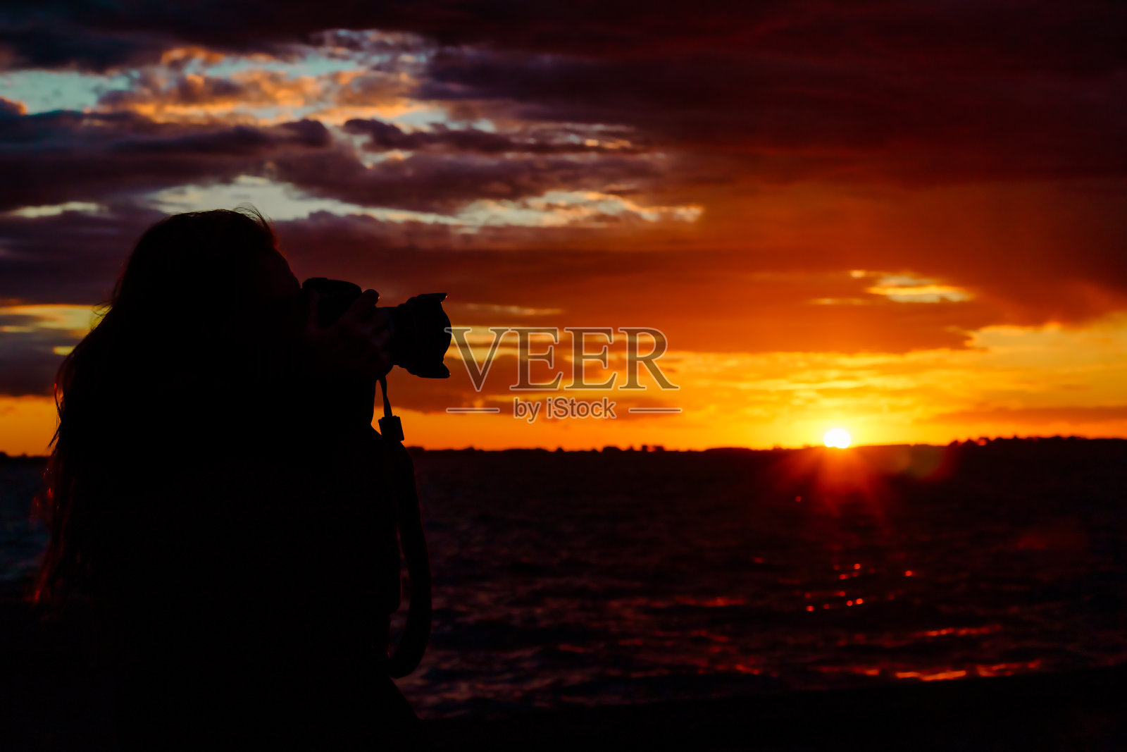 女摄影师的剪影在一个泻湖日落照片摄影图片