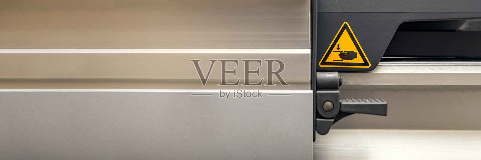 木工机器上的警告标志。某木工车间生产安全。活动部件的危险标志用手画在黄色三角形内照片摄影图片