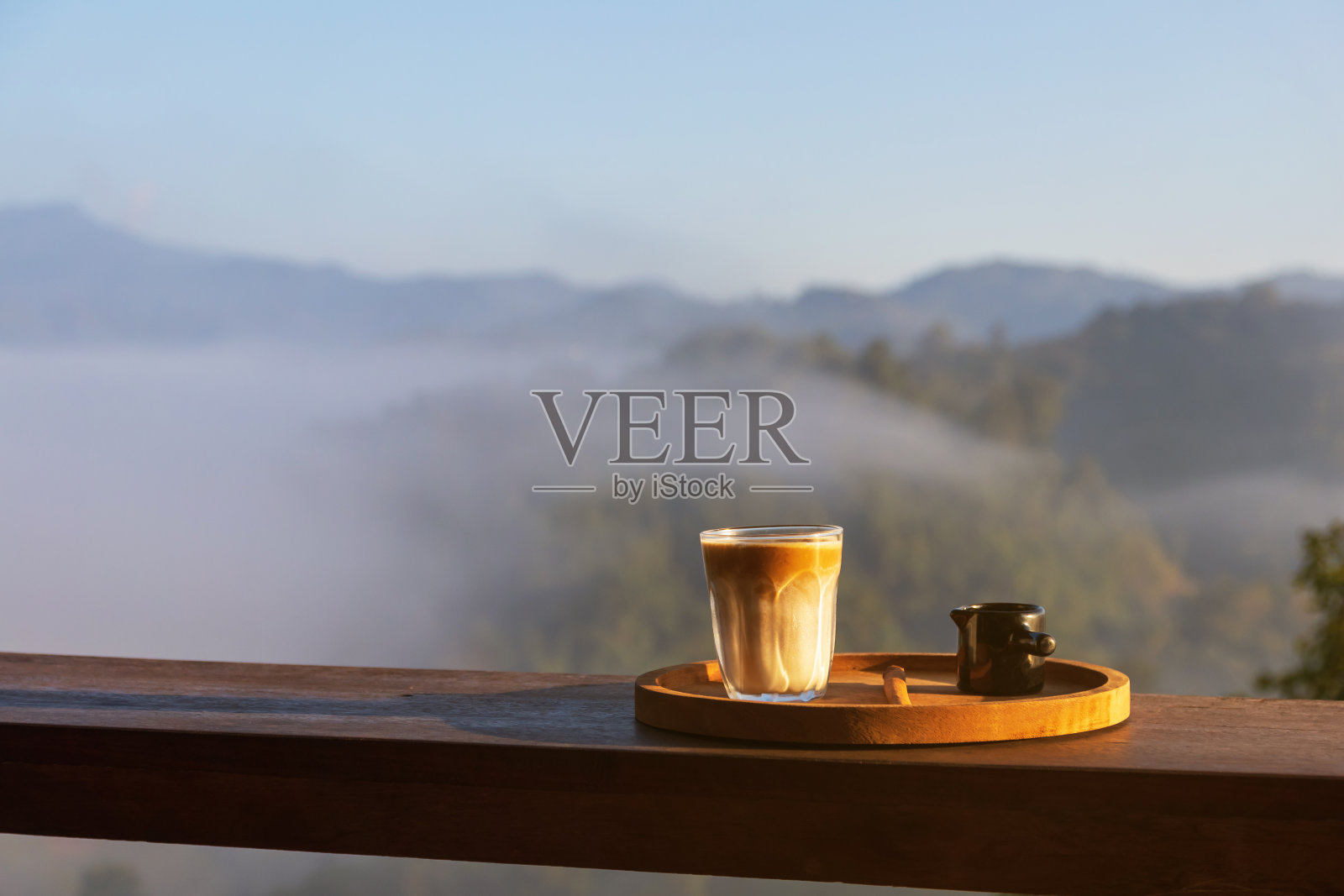 大自然中的日出咖啡。脏咖啡在木桌上与山雾在阴影的日出背景。早上好。照片摄影图片