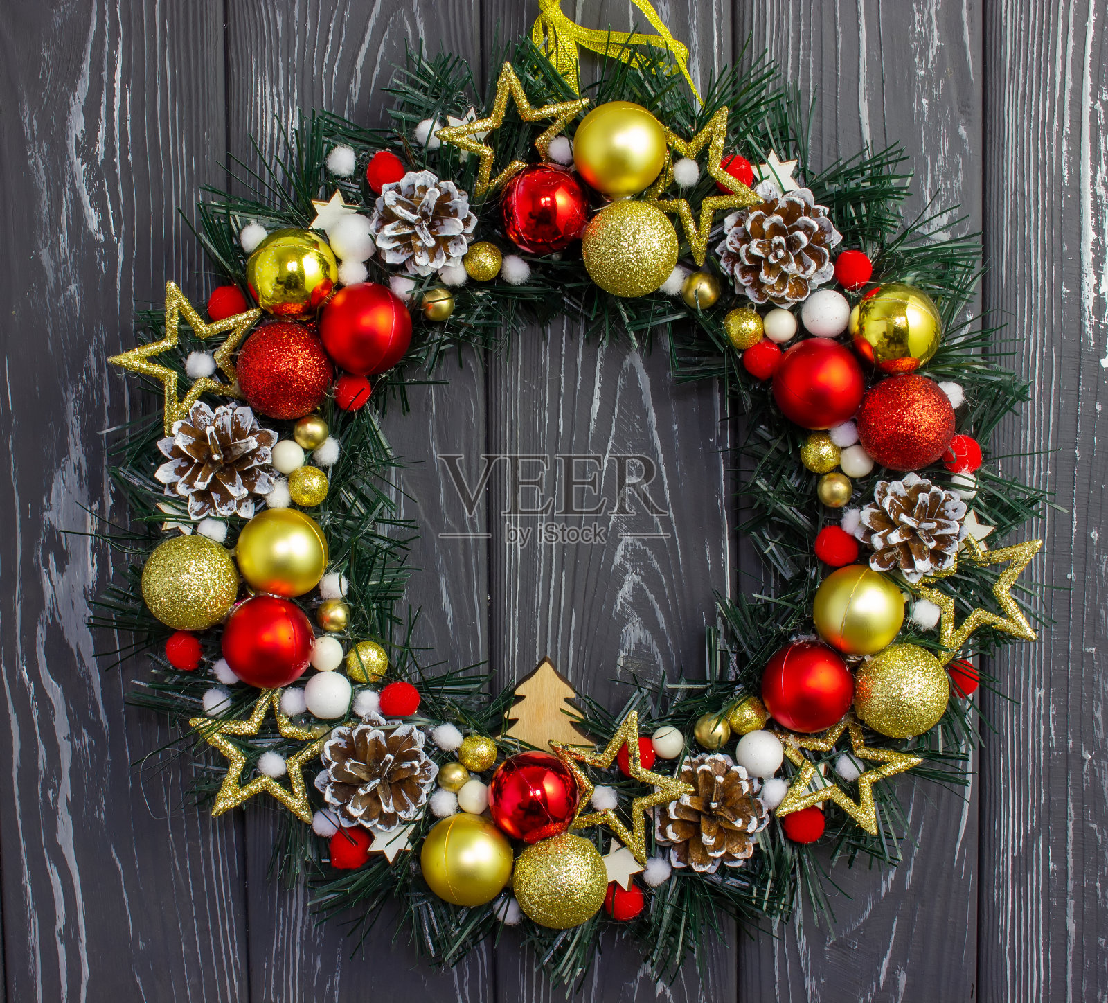 木制的墙上挂着圣诞球和玩具的圣诞花环。照片摄影图片