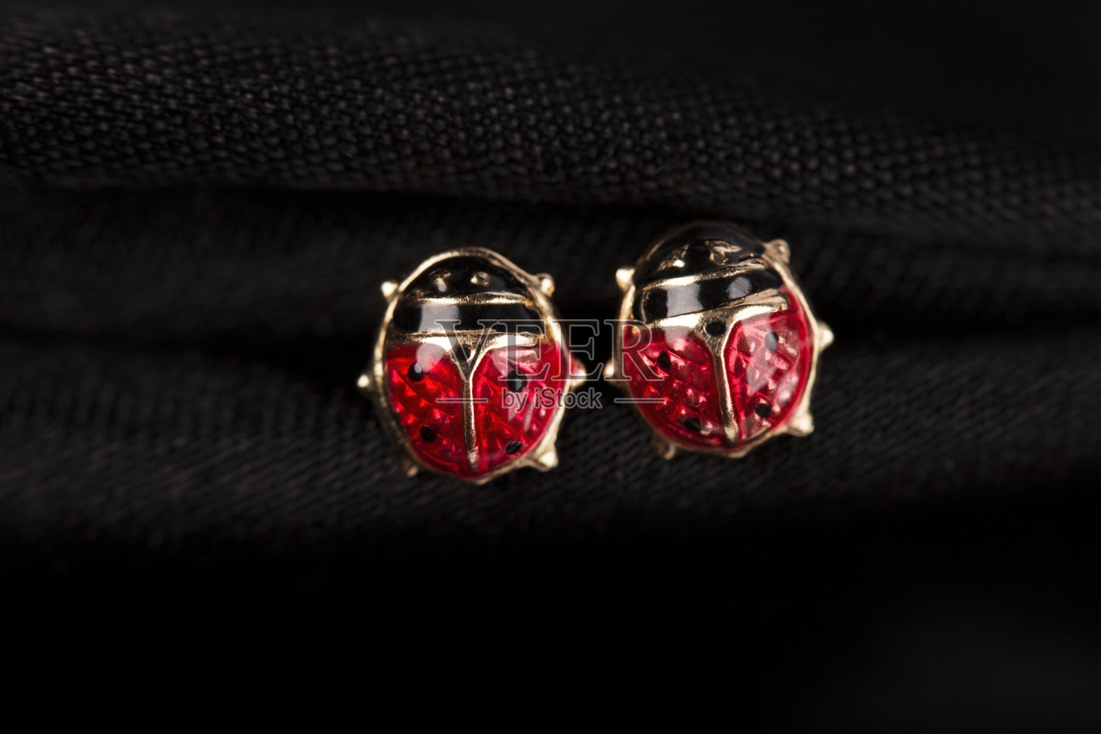 黑色背景上的瓢虫形状金色耳钉照片摄影图片