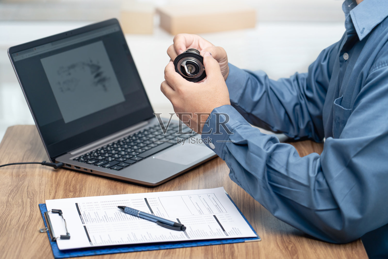 在汽车维修中心定期维修,手持汽车温控器,发动机使用笔记本电脑,检查新零件的库存,比较和检查汽车零件更换前的准确性照片摄影图片