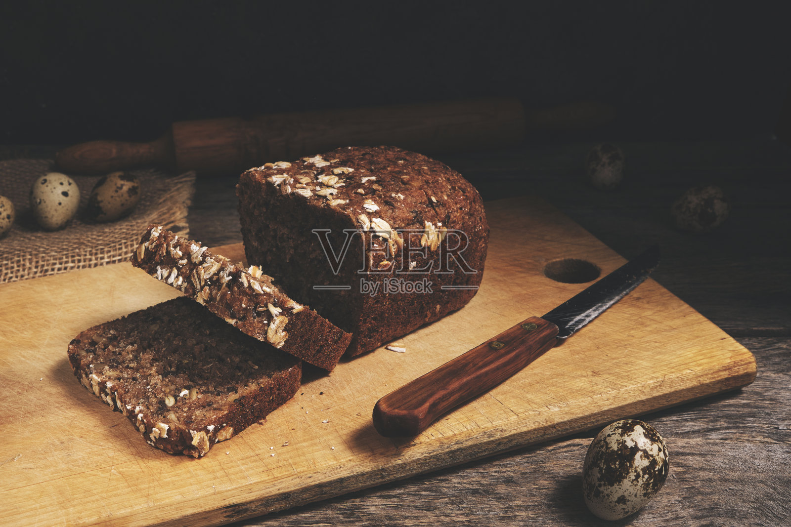 一条谷物片面包和鹌鹑蛋在一个旧的木制桌面俯瞰。照片摄影图片