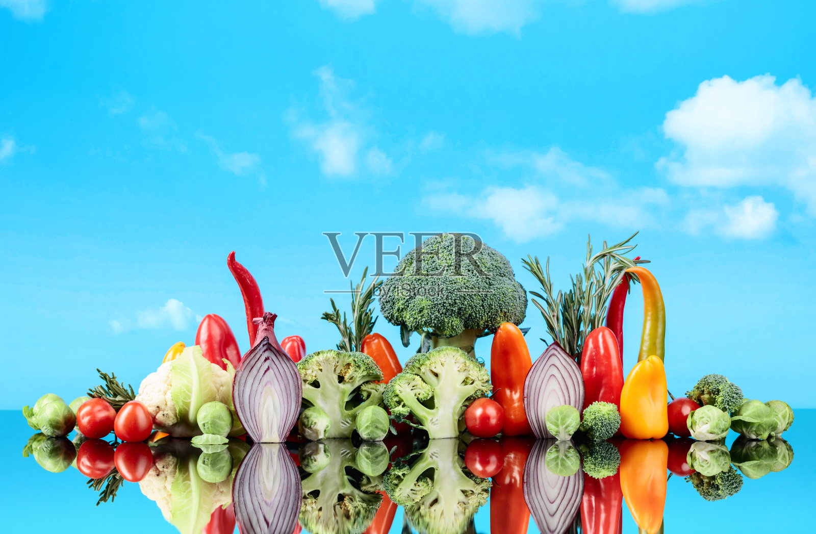 蓝色的天空衬托着各种各样的生蔬菜。照片摄影图片