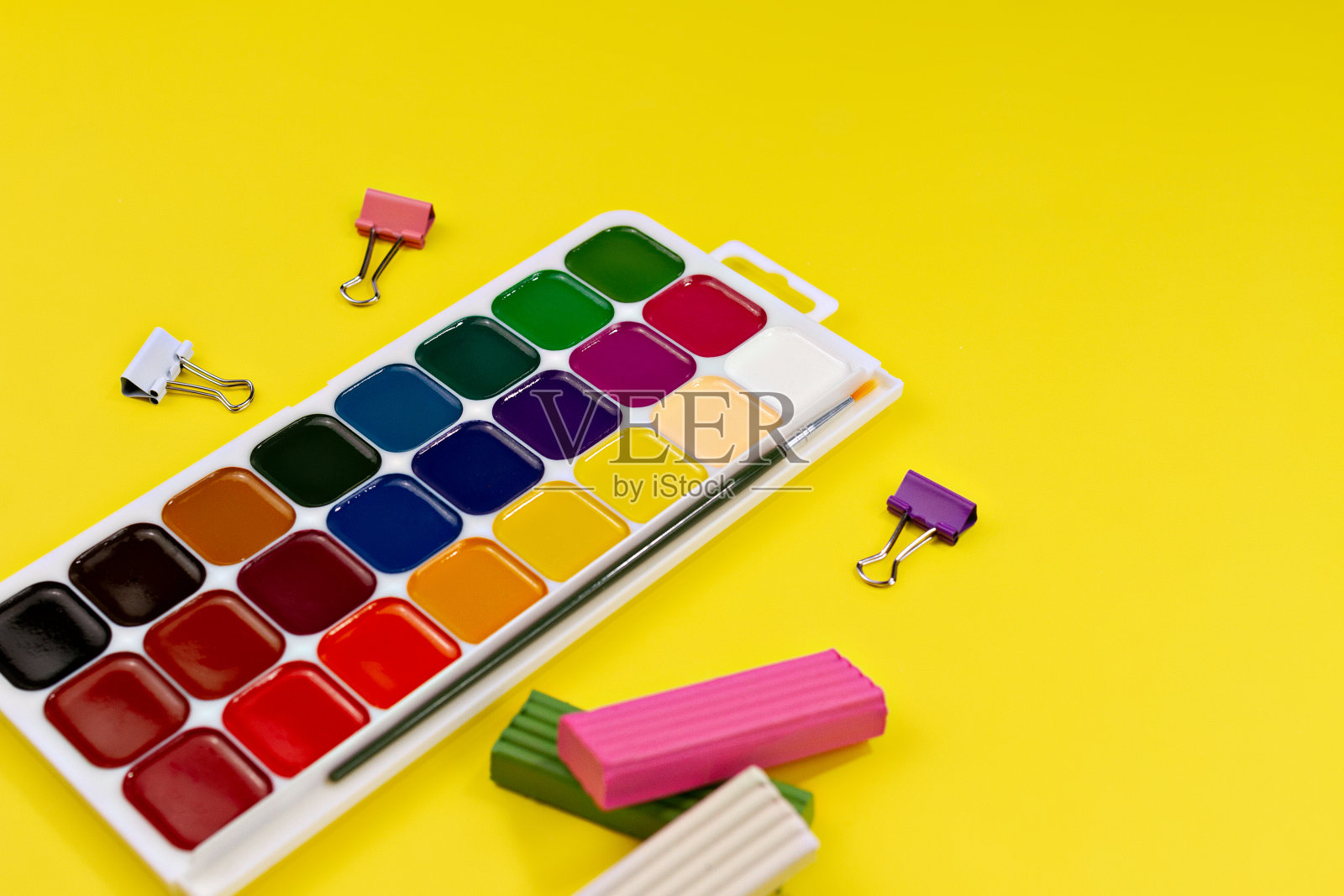 水彩颜料和回形针,黄色背景上的多色橡皮泥照片摄影图片