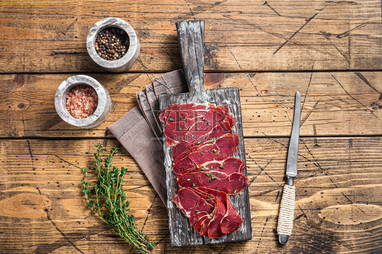 熏牛肉片,牛肉和香草放在木板上。木制背景。俯视图照片摄影图片