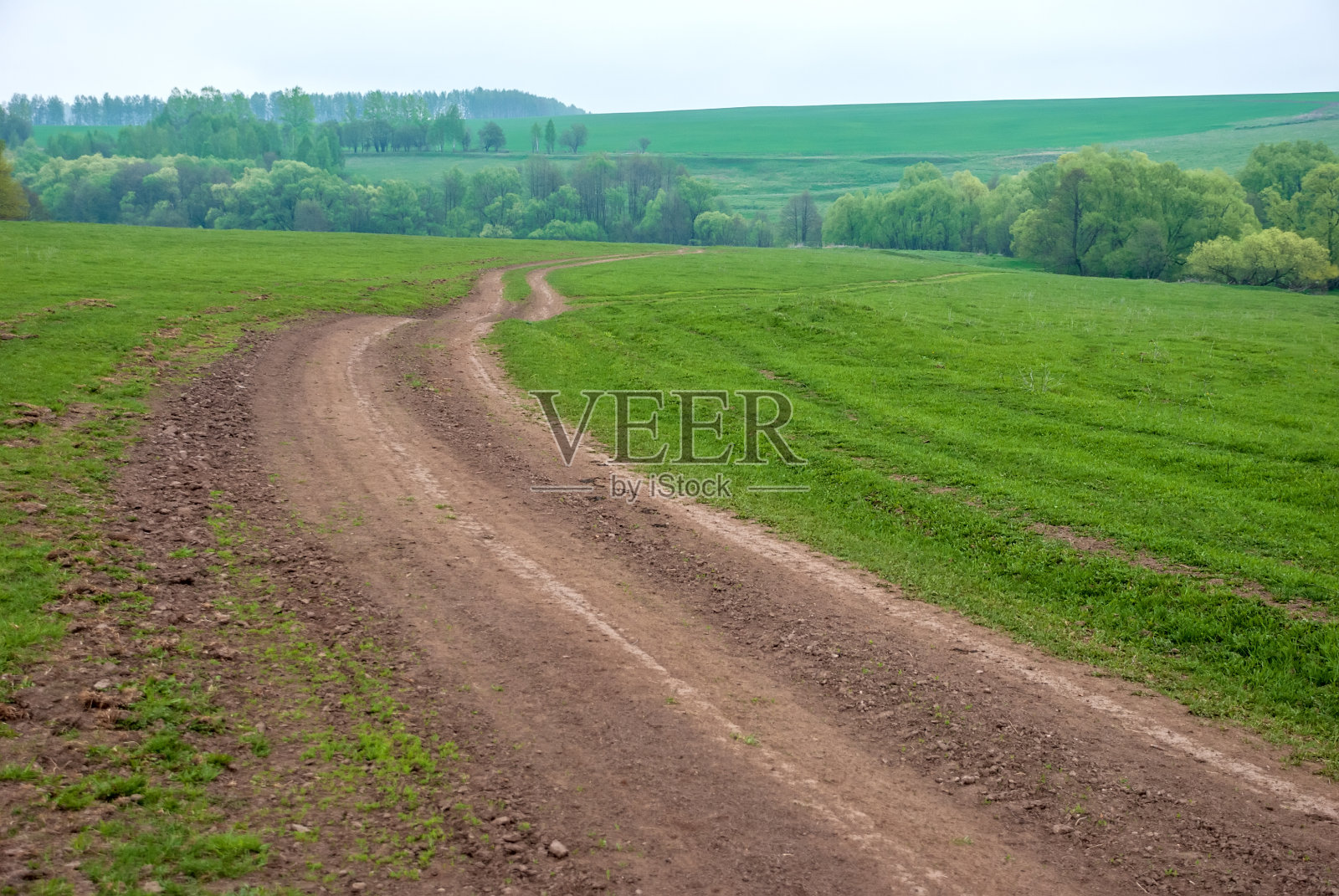 农村土路在农村地区。绿色的田野,树木和美丽的云彩的天空。美丽的春天景色。照片摄影图片
