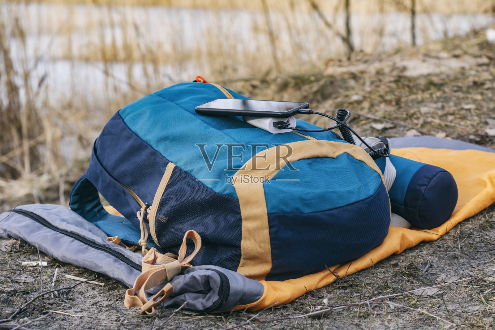 智能手机使用便携式充电器充电。Power Bank在户外用背包为手机充电,以自然和河流为背景进行旅游。照片摄影图片