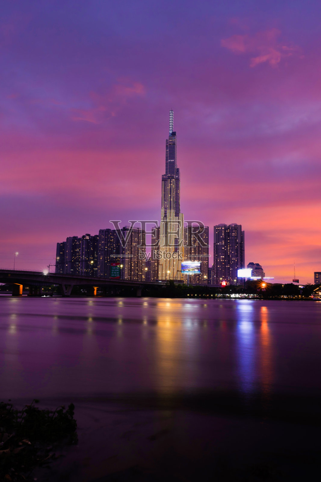 地标81的日落景象——这是一座超高的摩天大楼和西贡桥,西贡河沿岸的开发建筑灯光柔和下来照片摄影图片