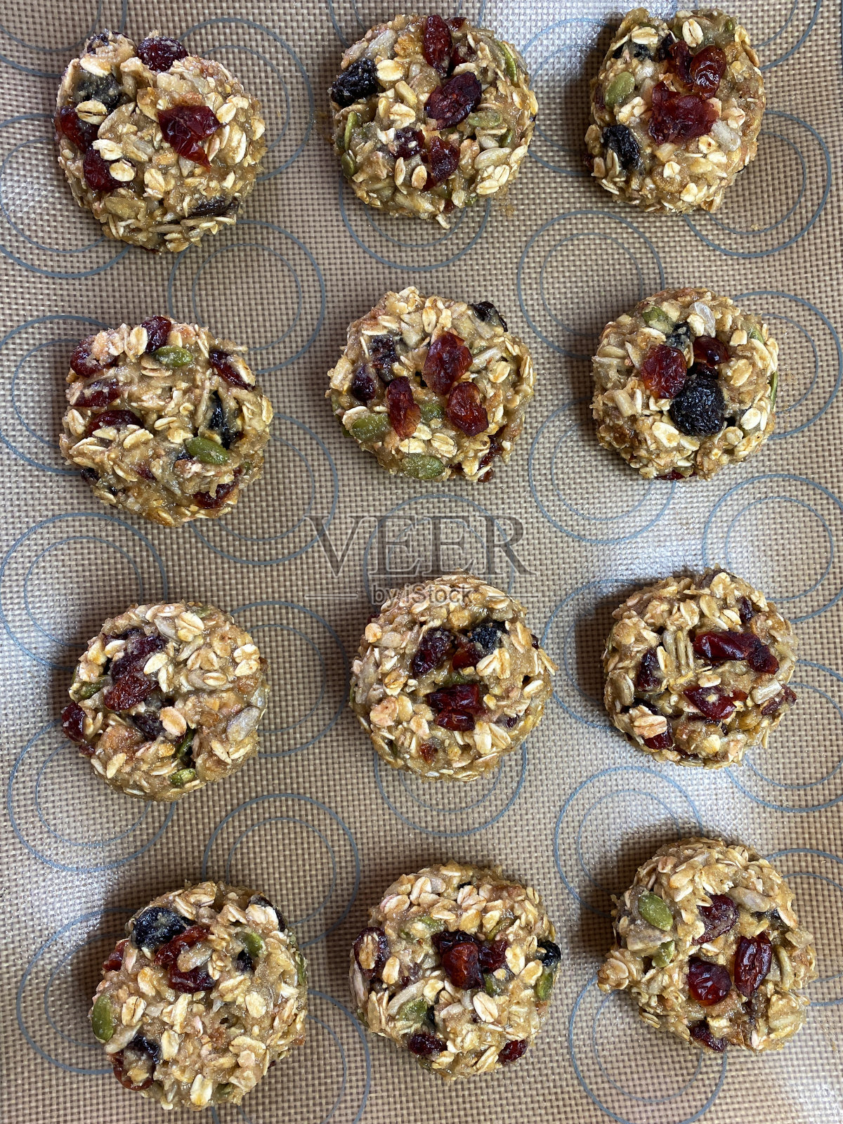 全帧图像的一排排自制燕麦和干果饼干在硅胶烘烤板上,家庭烘烤,高架视图照片摄影图片