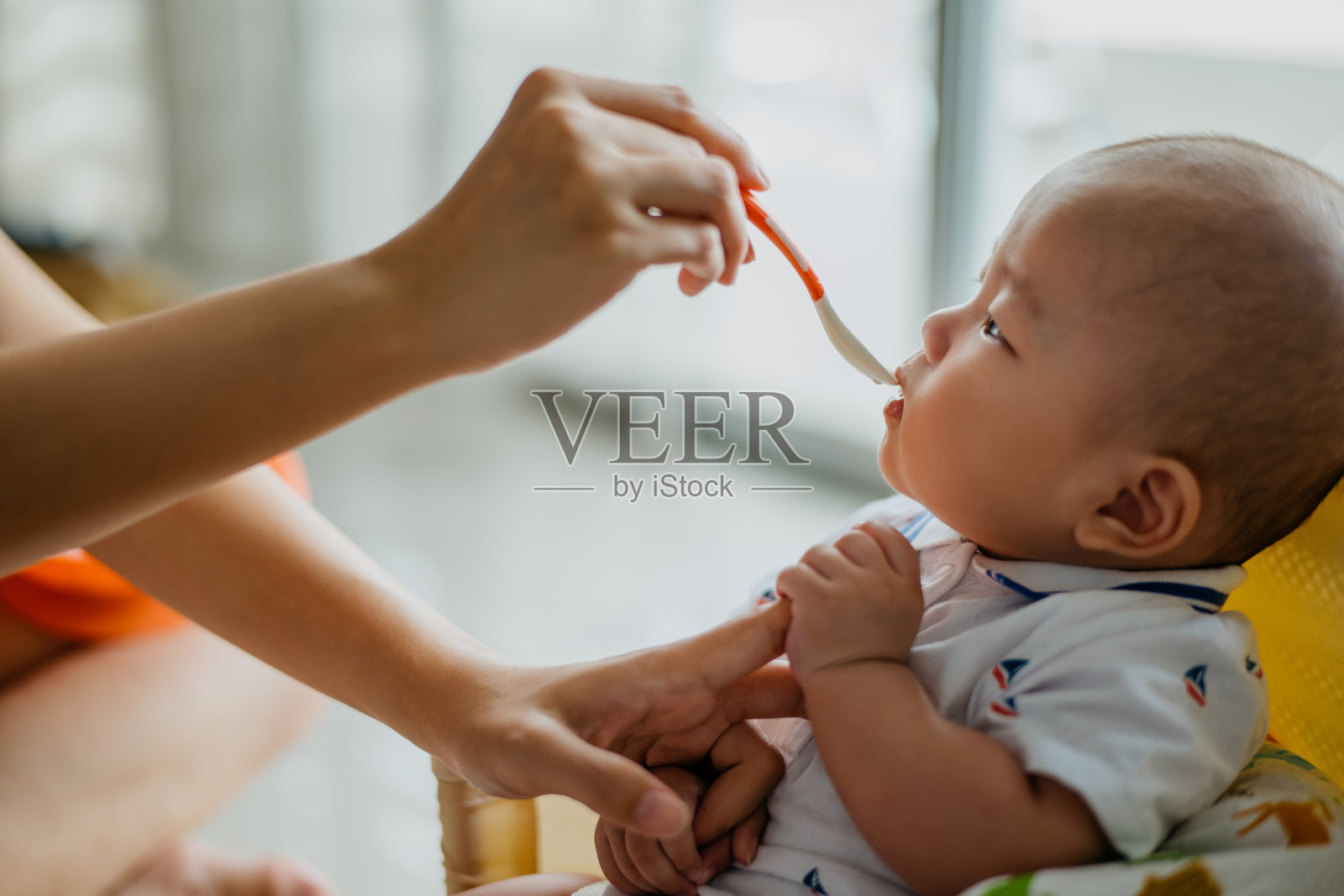 母亲用勺子喂她的婴儿照片摄影图片