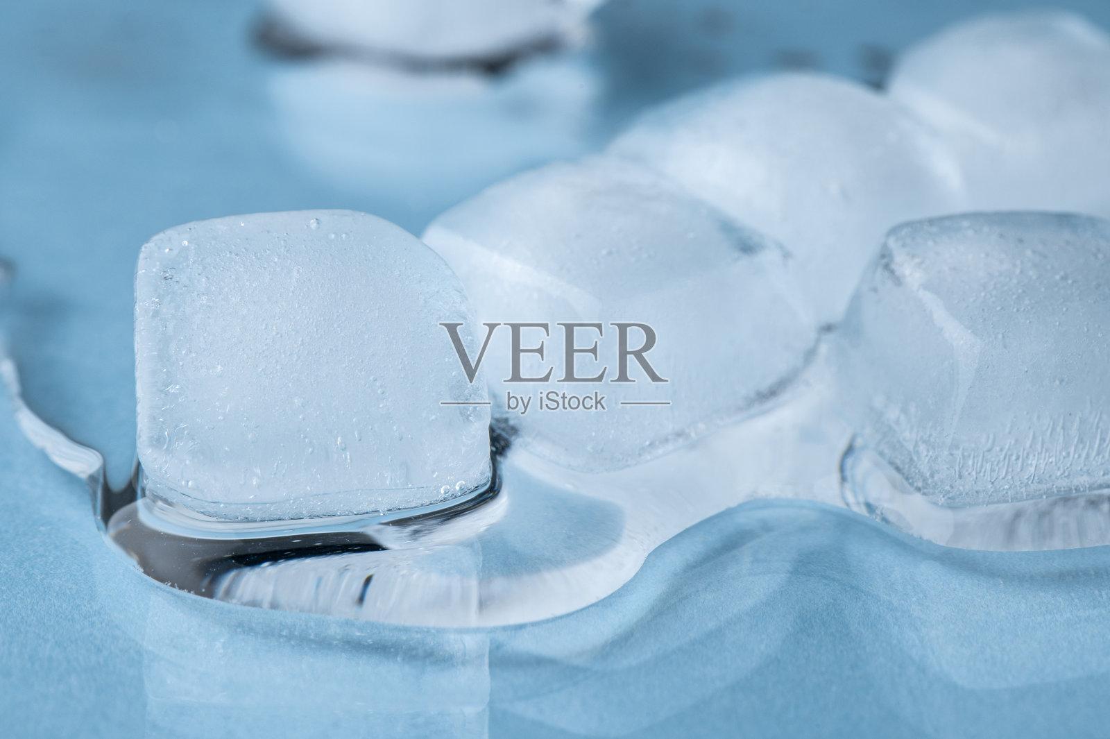 蓝色背景上的冰块和水滴。照片摄影图片