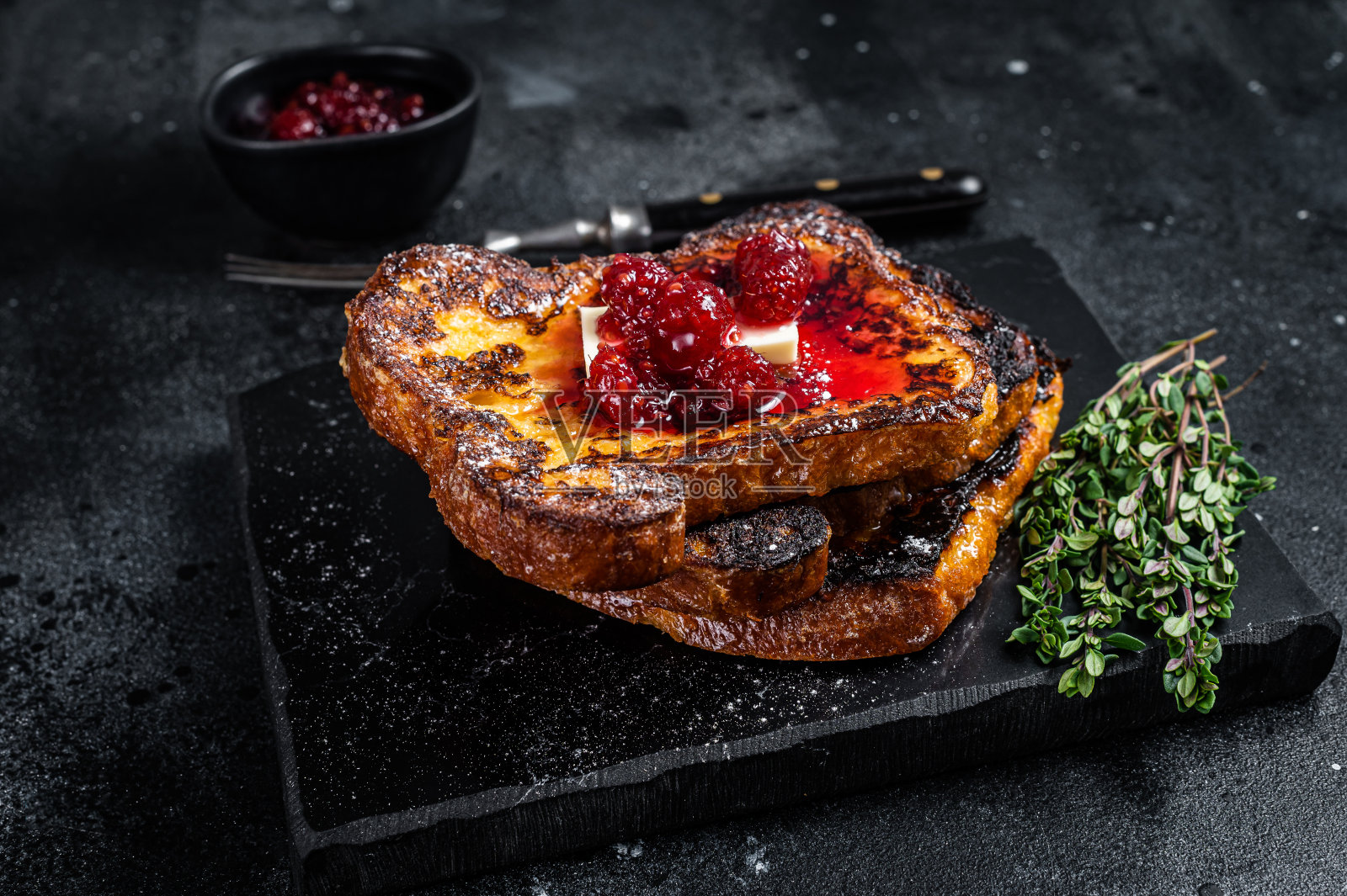 覆盆子法式吐司配黄油,放在大理石板上。黑色背景。俯视图照片摄影图片