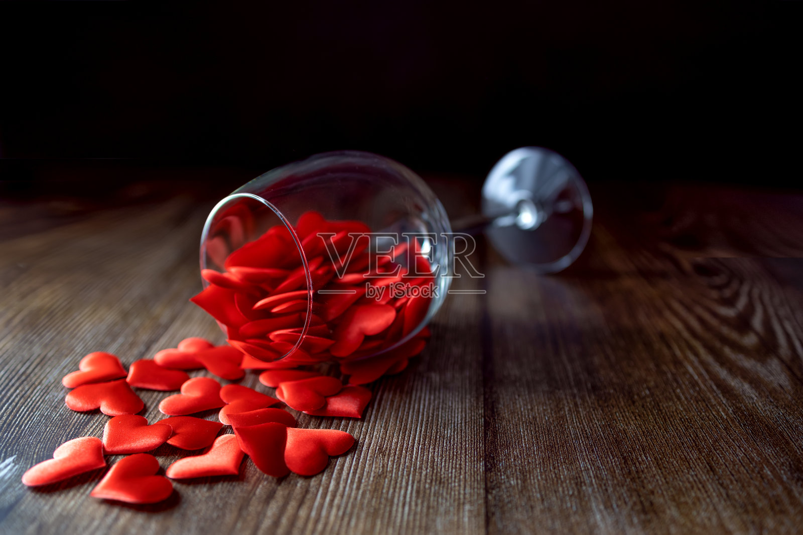 杯子里装满了黑色背景上的红心。情人节。照片摄影图片