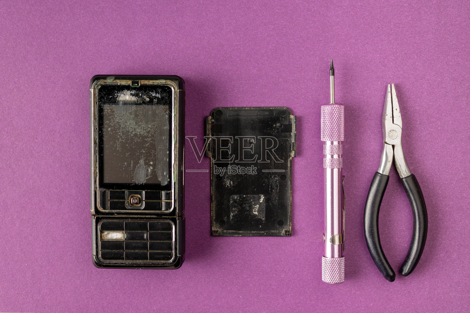旧的破手机和修理工具在紫丁香背景照片摄影图片
