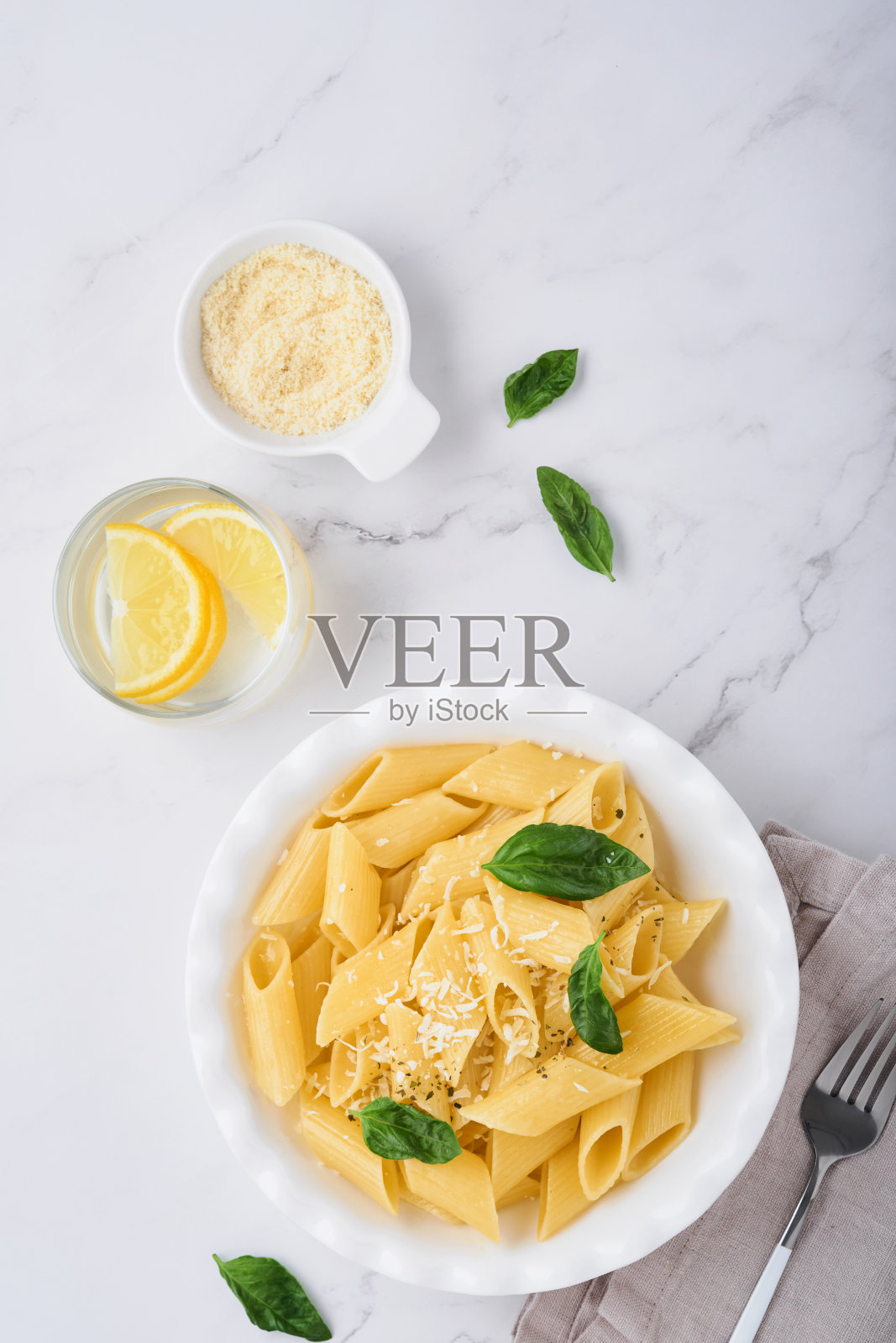 美味可口的经典意大利通心粉与帕尔马干酪和罗勒在白色的盘子在石头桌子上盘子。意大利传统菜肴。前视图。照片摄影图片