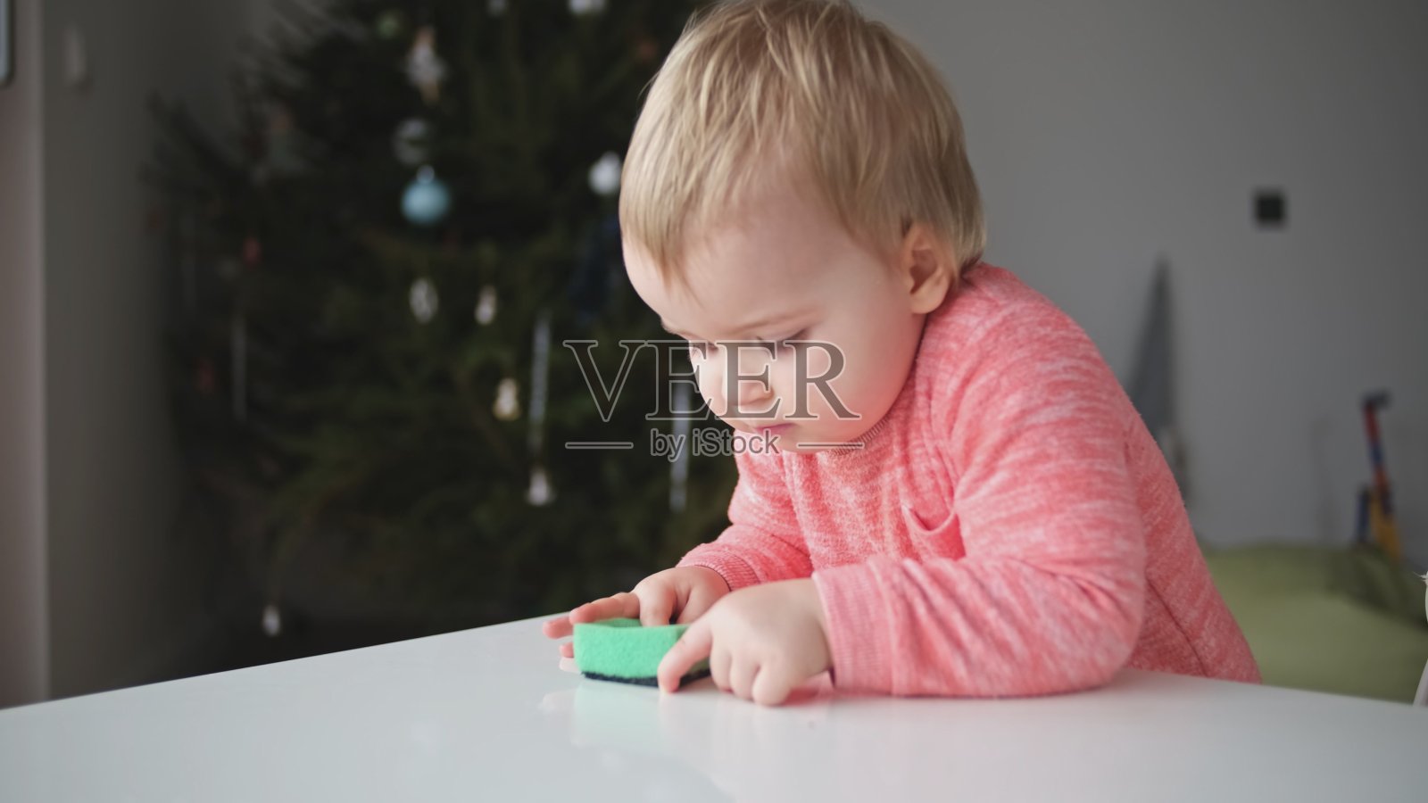 可爱可爱的白人幼小女孩用厨房海绵激情和喜悦清洁桌子表面照片摄影图片