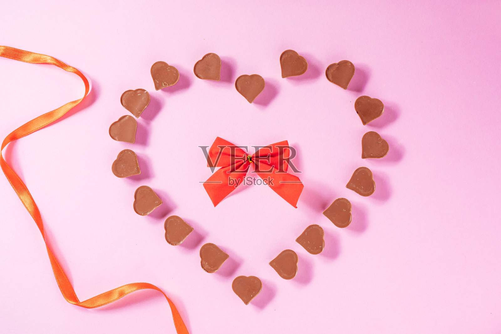 粉色背景红色丝带心形巧克力,情人节概念照片摄影图片