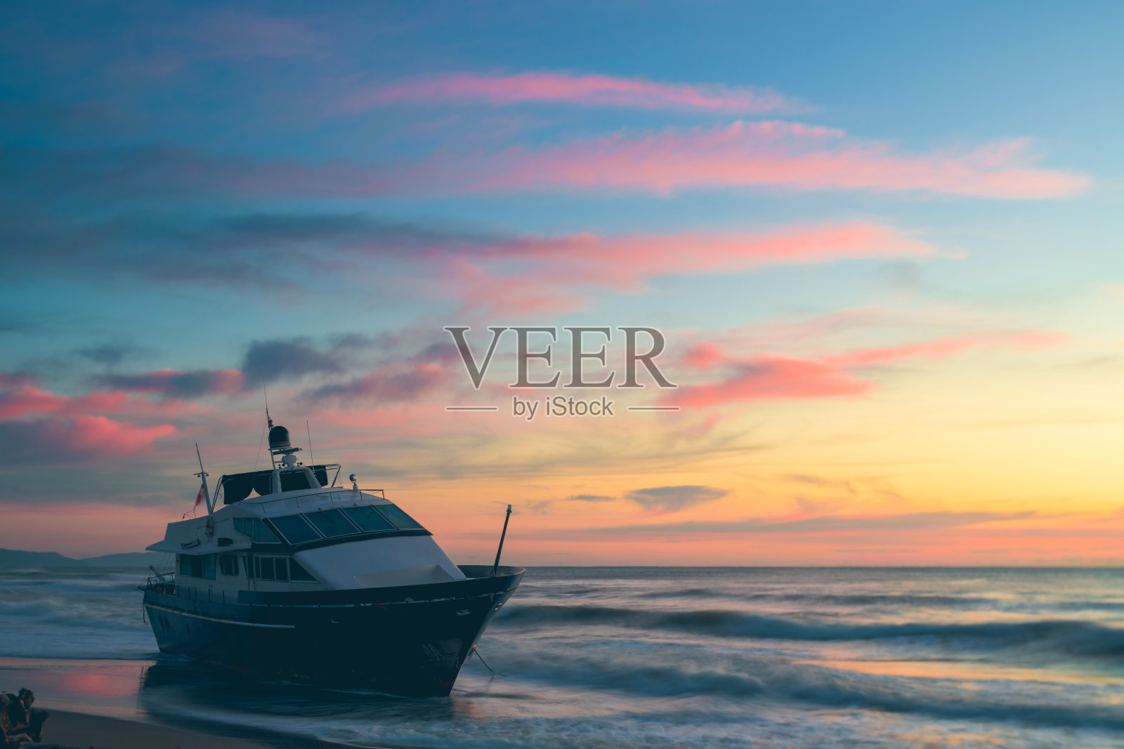 船搁浅在日落的沙滩上照片摄影图片