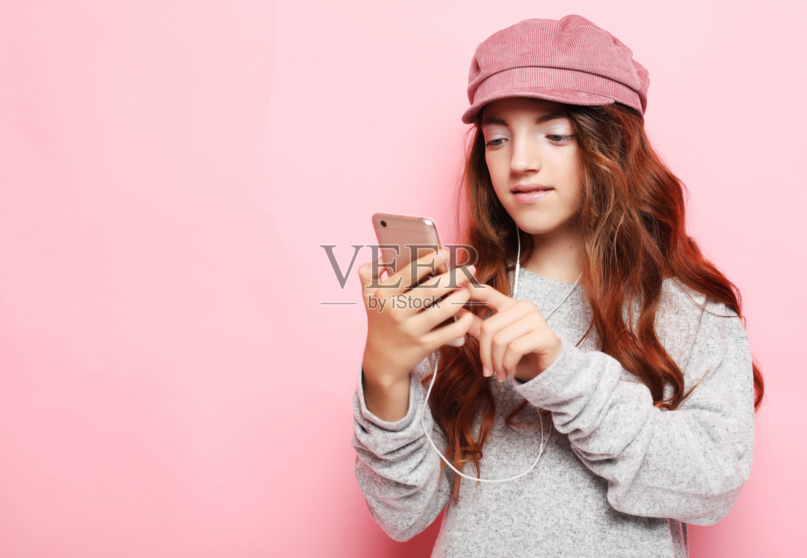 小女孩用粉色背景的智能手机,近看照片摄影图片