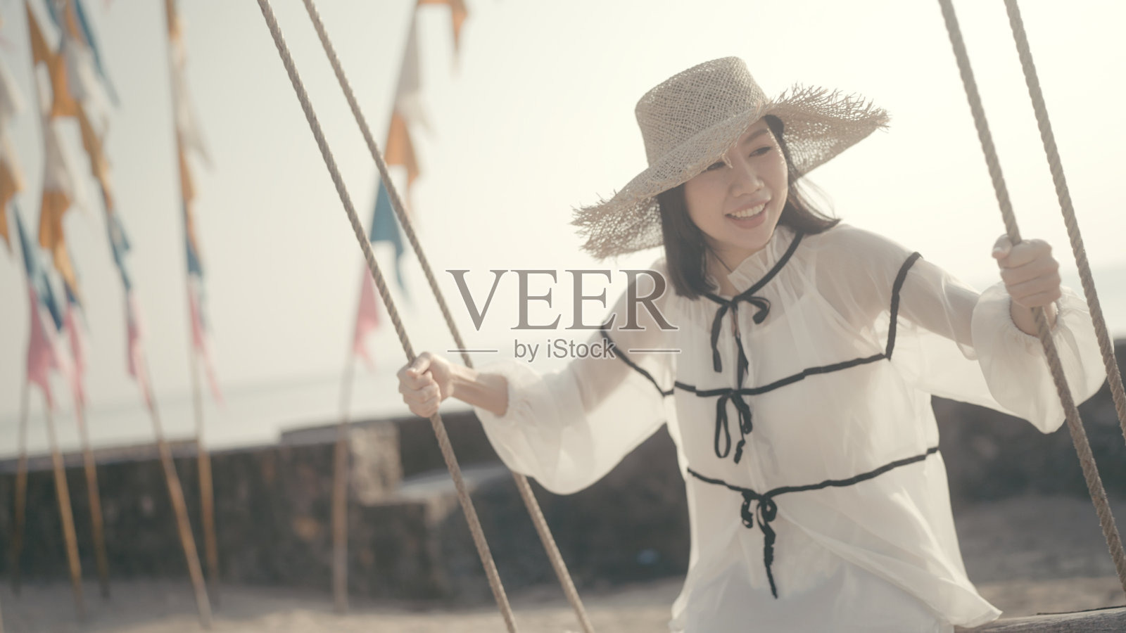 一个快乐的女人在海边的沙滩上荡秋千照片摄影图片